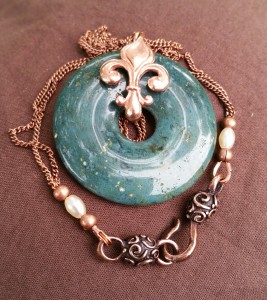 moss agate donut with red bronze fleur-de-lis, and copper chain with precosia seed beads