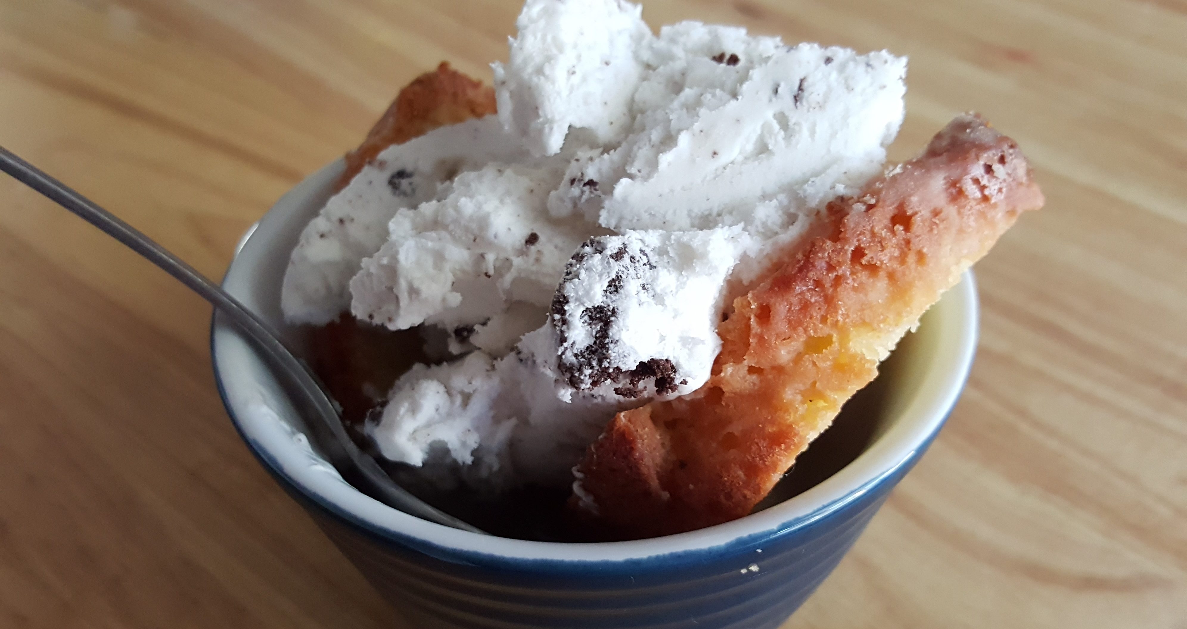 Almond cake in a blue ramekin topped with creamy cookies and cream ice cream